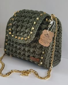 a green purse with gold rivets on the front and chain hanging down from it