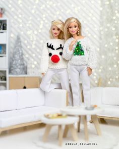 two dolls standing next to each other in front of a white couch and christmas tree