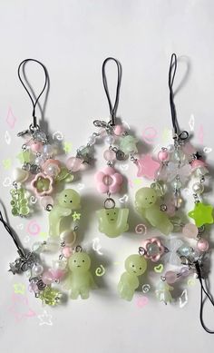 a bunch of charms that are on a white surface with pink, green and yellow colors