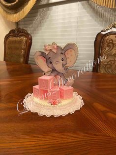 an elephant figurine sitting on top of a table next to a pink cake