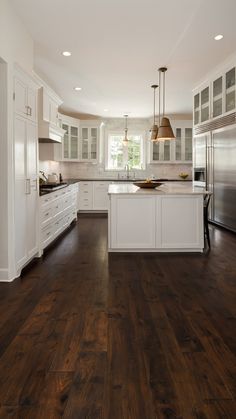 a large kitchen with white cabinets and wood floors