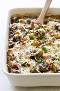 an eggplant casserole in a white dish with a wooden spoon