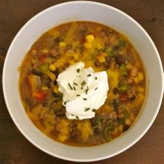 a white bowl filled with soup and sour cream sitting on top of a wooden table