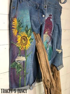 an old pair of jean shorts with sunflowers painted on them, hanging from a wall