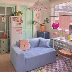 a blue couch sitting in front of a window next to a table with a stuffed animal on it