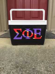 a cooler with the word zoo painted on it sitting in front of a red door