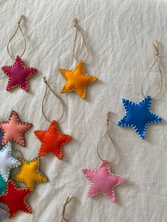 five different colored stars hanging from strings on a white sheet with twine string attached to them