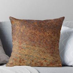 an old rusted surface throw pillow on a couch with white pillows and grey walls