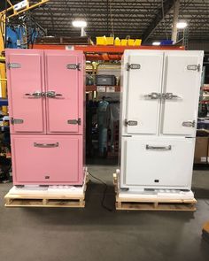 two pink and white refrigerators sitting side by side in a warehouse with pallets