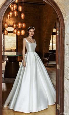 a woman in a white wedding dress standing by an open doorway with lights hanging from the ceiling