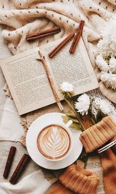 a cup of coffee sitting on top of a white plate next to an open book