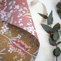 an umbrella with flowers and leaves on it next to a roll of toilet paper that has been rolled down