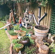 a little boy standing next to a wooden barrel filled with plants and potted plants