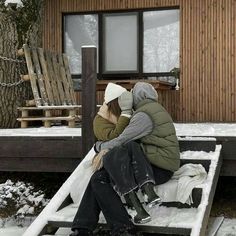 two people sitting on a bench in front of a cabin