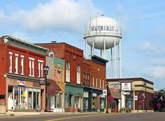 an empty street with buildings and a water tower in the background