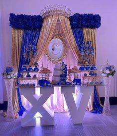 a table with blue and gold decorations in front of a large sign that says xxv