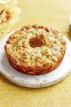 a cake sitting on top of a white plate next to a yellow tablecloth and flowers