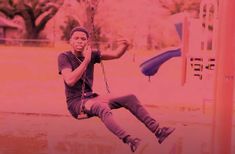 a man sitting on a swing at a park in front of a pink and red background