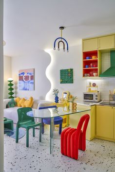 a colorful kitchen and dining area with yellow cabinets, green chairs, and white tile flooring