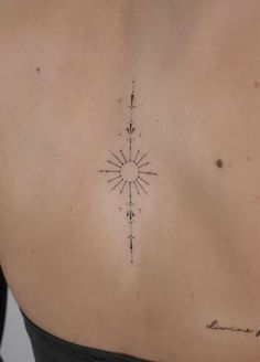 a woman's back with a small compass tattoo on her left side ribcage