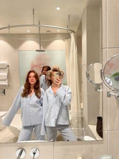 three women in pajamas are standing in front of a bathroom mirror and taking a selfie