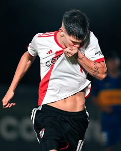 a young man kicking a soccer ball on top of a field