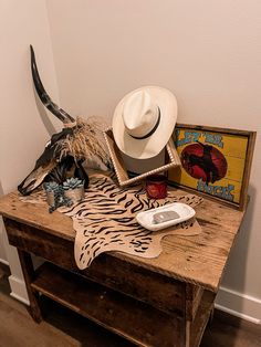 a wooden table topped with a white hat and animal print cow skin on top of it