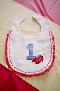 a bib with the number one on it sitting on top of a pink blanket