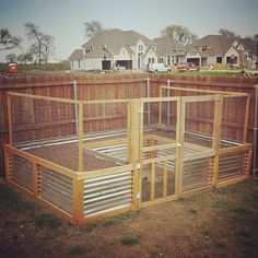 an outdoor chicken coop in the middle of a yard with houses in the back ground