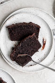 two plates with slices of chocolate cake on them and one has a fork in it