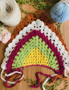 three crocheted granny hats sitting on top of a wooden table next to yarn