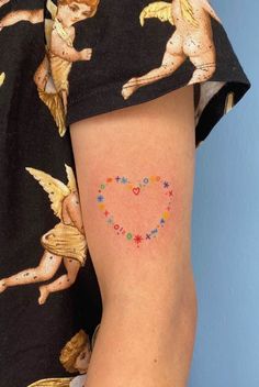 a woman with a small tattoo on her arm that has hearts and stars in the shape of cupids