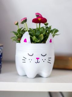 a white cat planter with flowers in it