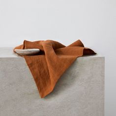 an orange cloth is laying on top of a concrete block with a white wall in the background