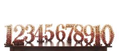 the letters are made out of beads on a wooden stand with a white wall in the background