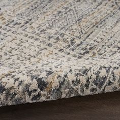 an area rug on top of a wooden floor with a brown and white color scheme