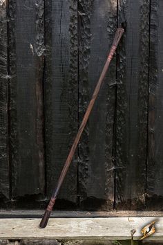 an old, wooden walking stick leaning against a fence