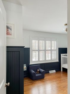 a living room with hard wood floors and dark blue walls, along with a white crib