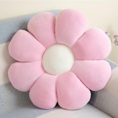 a pink flower shaped pillow sitting on top of a bed