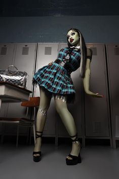 a woman in a plaid dress standing next to lockers with her hands on her hips