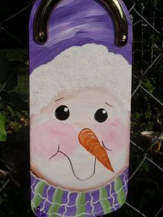 a hand painted snowman with a carrot on it's nose hanging from a chain link fence