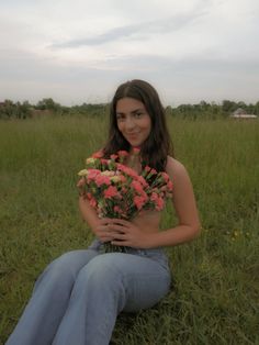 a woman sitting in the grass holding flowers