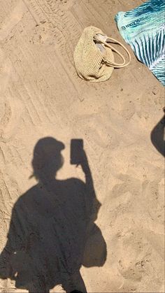 the shadow of a person holding a cell phone in front of a hat and bag