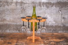 a wine glass holder with four wine glasses on it and a bottle in the middle