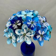 a blue vase filled with paper flowers on top of a table