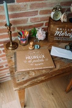 a wooden table topped with a notebook next to a candle and other items on top of it