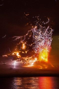 fireworks are lit up in the night sky over water and clouds with bright lights on them