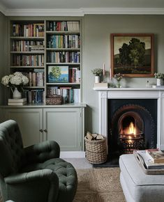 a living room filled with furniture and a fire place in front of a bookshelf