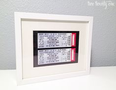 a couple of tickets sitting in a white frame on top of a table next to a wall