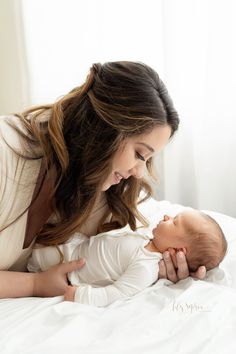 a woman laying on top of a bed holding a baby